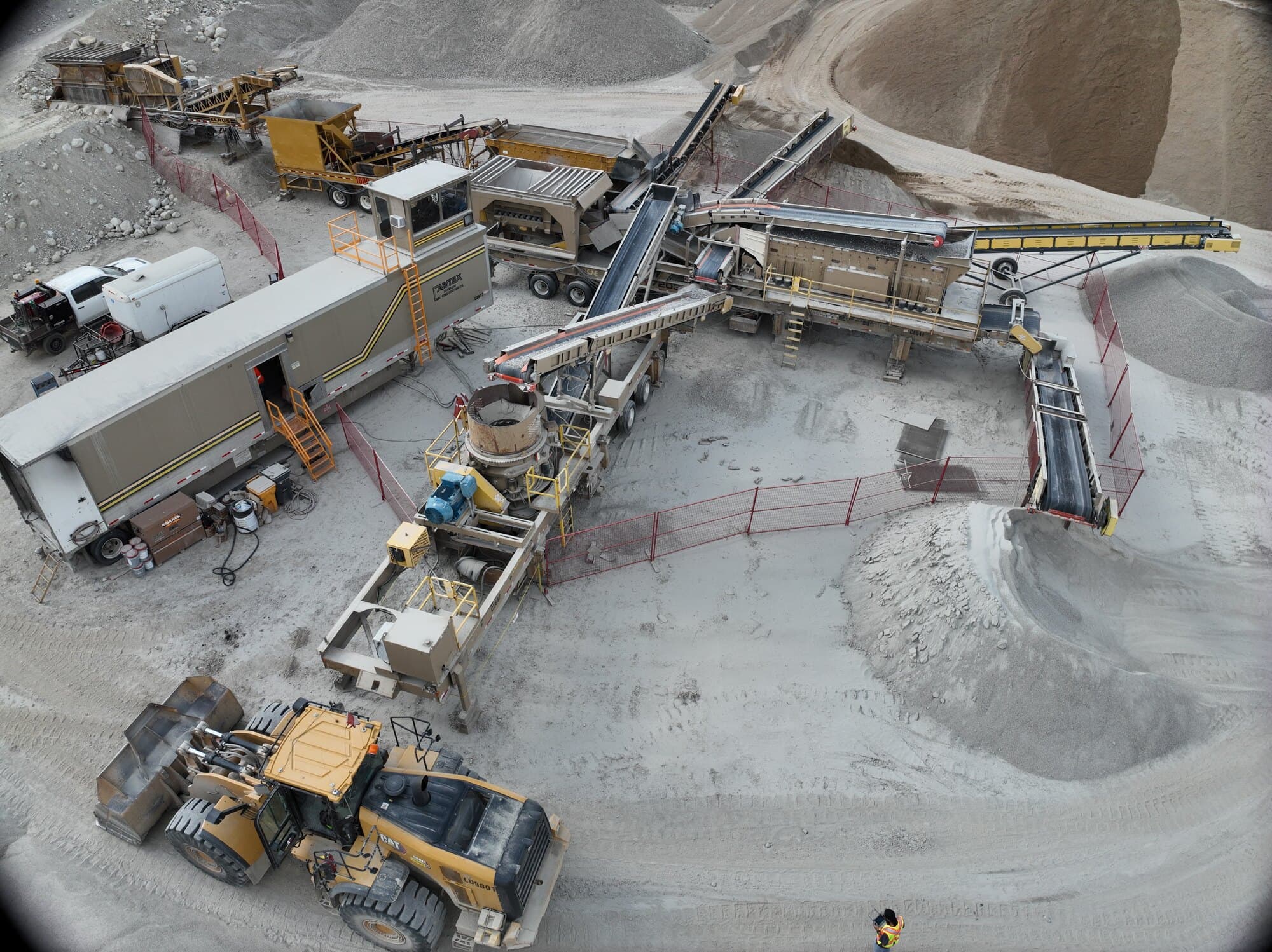A close drone view of a Cantex cone crusher and screen deck in a running spread, with the site trailers alongside.
