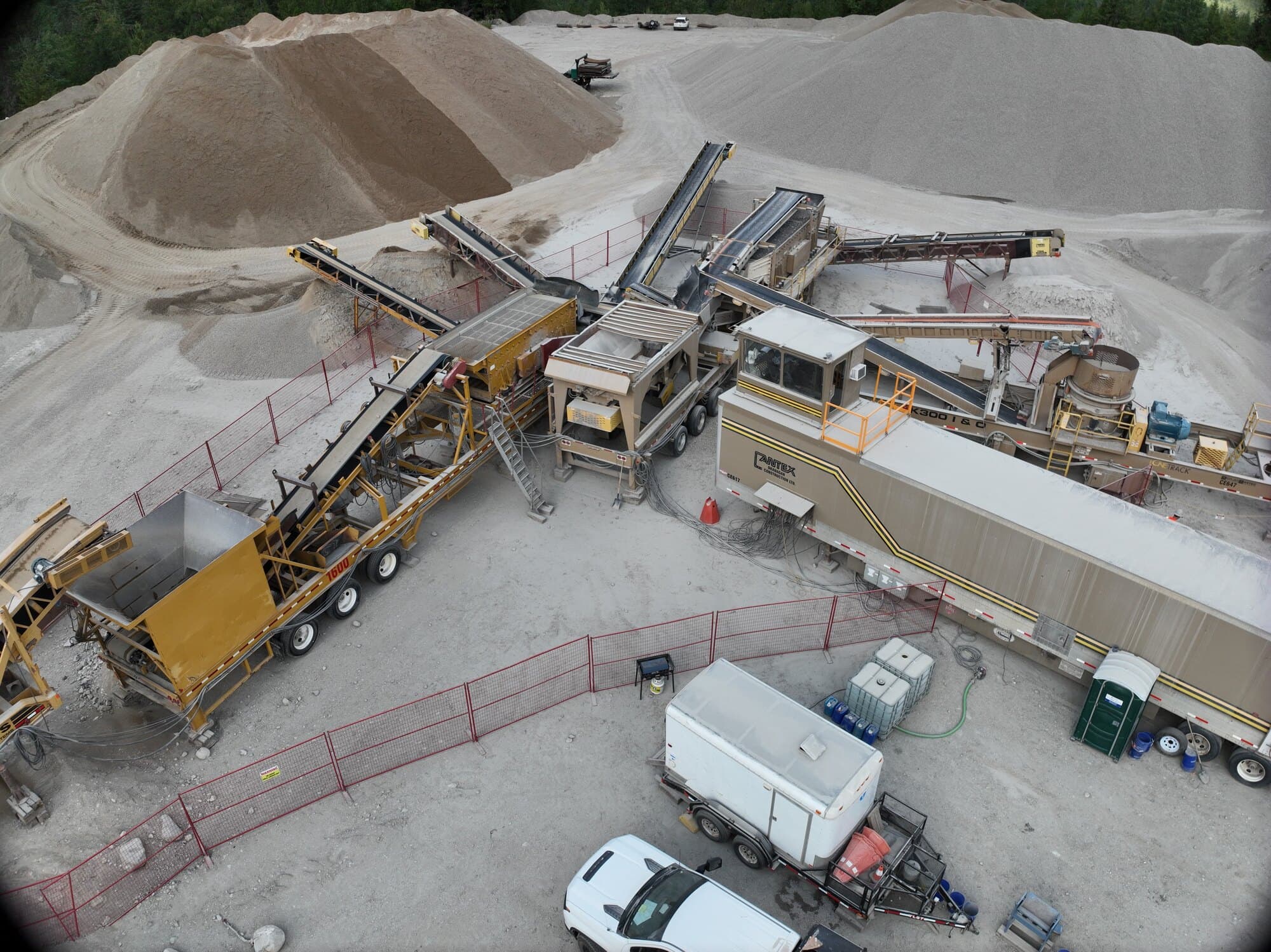 A Cantex crushing spread from the air with graded stockpiles laid out around it and the pit face behind.