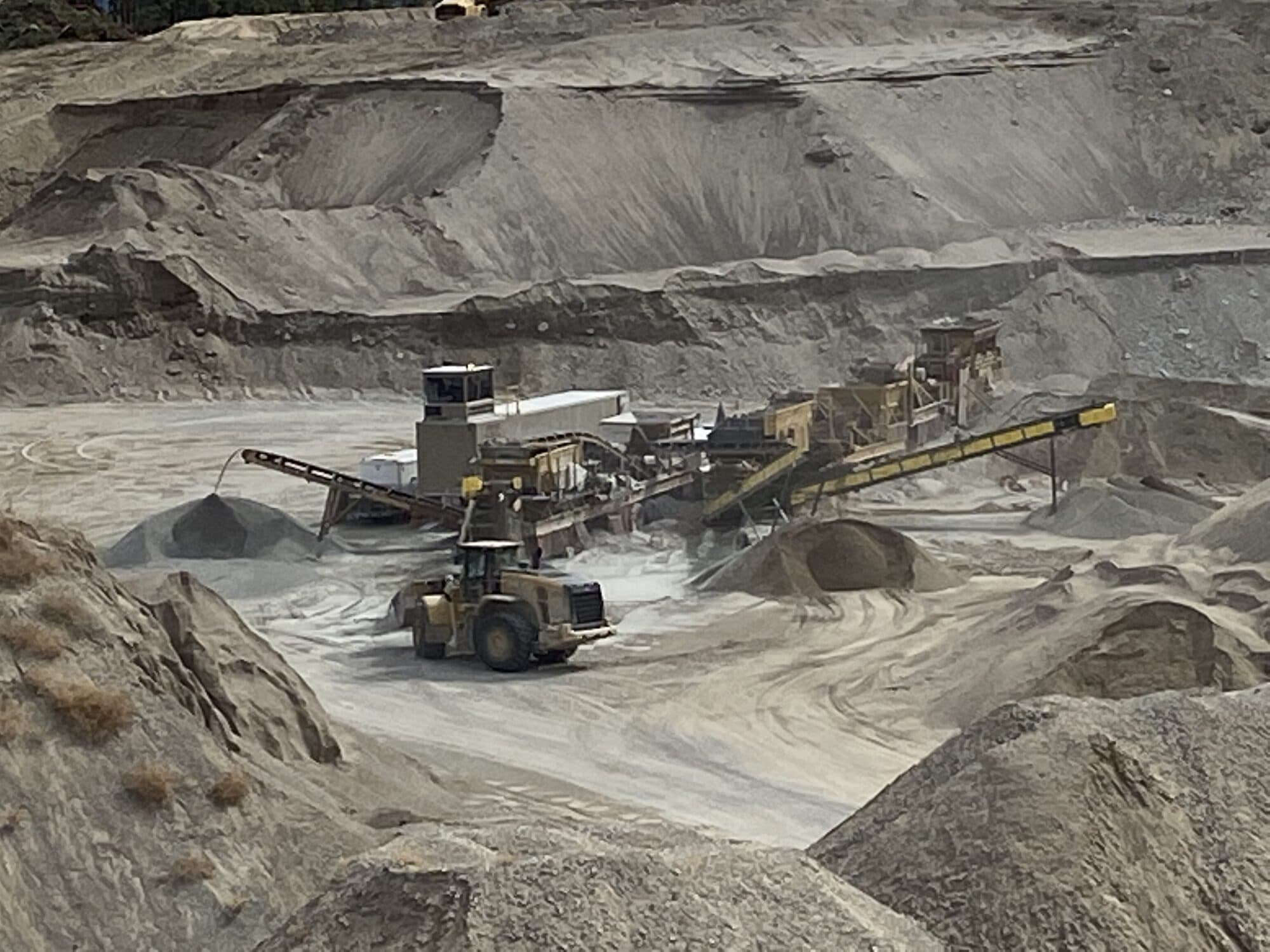 A Cantex crushing plant and wheel loader working terraced pit benches, producing crushed road base.