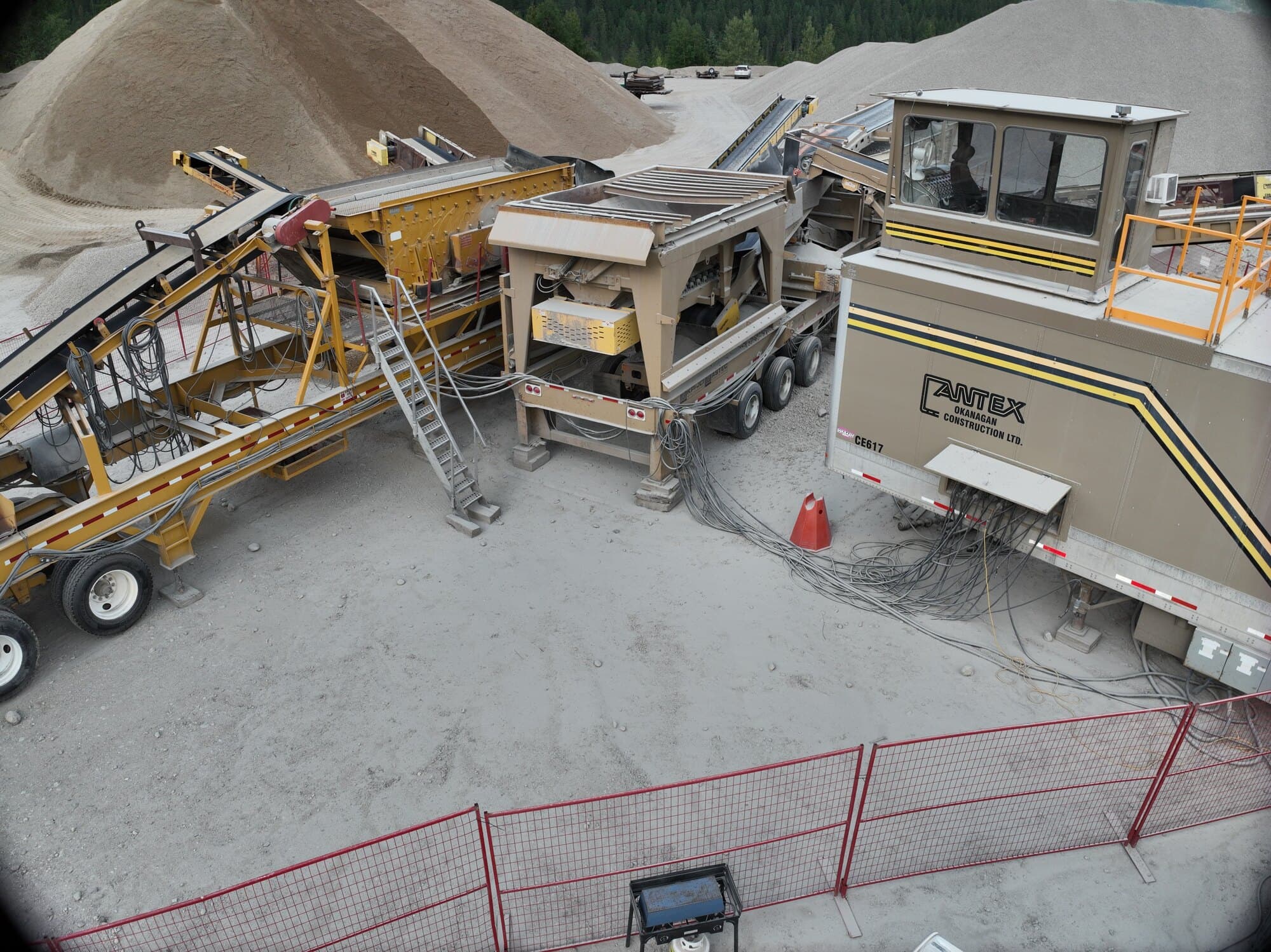 A Cantex screen deck on its trailer beside the Cantex Crushing site trailer, with the feed conveyor running into it.