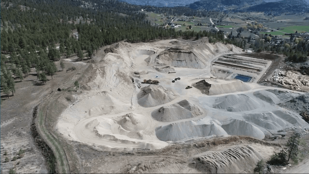 Aerial view of the Cantex Crushing gravel pit at Summerland, BC, with stockpiles and terraced benches.