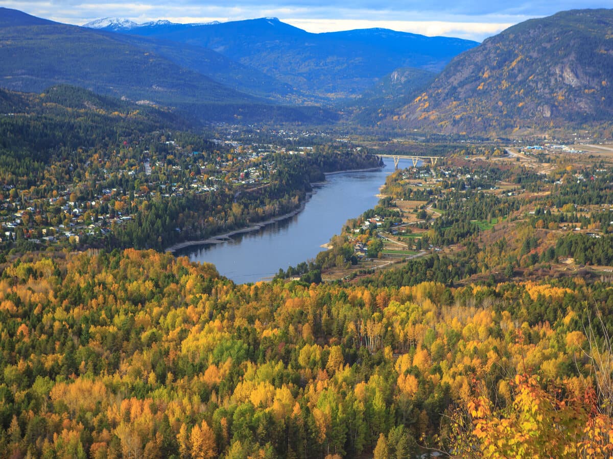 Autumn colours along the Columbia River at Castlegar, with the town and the Selkirk Mountains beyond.