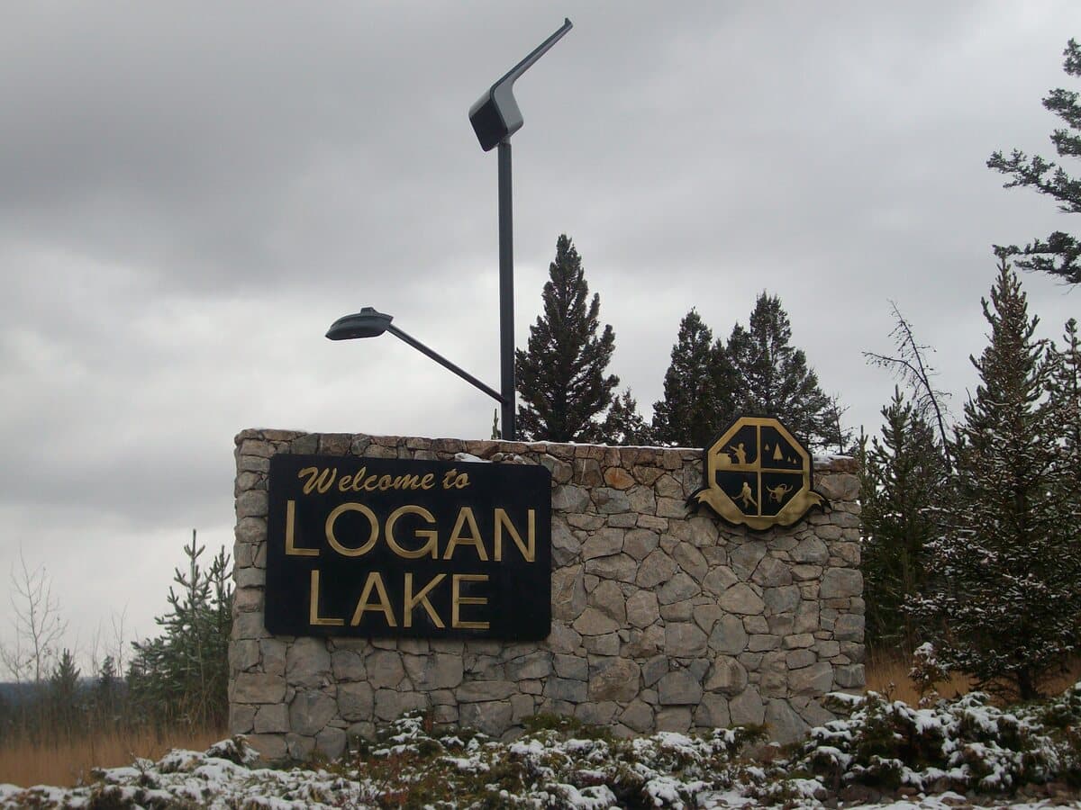 The stone "Welcome to Logan Lake" sign at the entrance to the community, framed by evergreens.